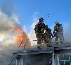 Firefighters on roof of a house on fire